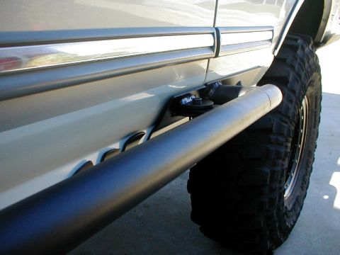 1996 Ford Bronco - This image shows the side of a vehicle equipped with aftermarket rock sliders and aggressive off-road tires.