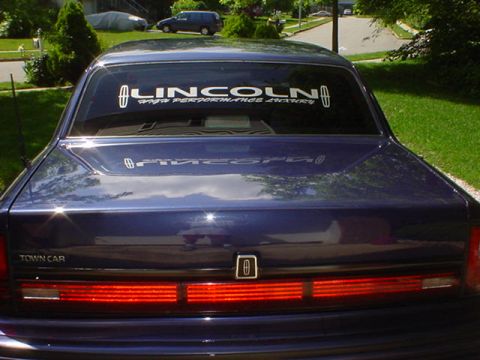 1994 Lincoln Town Car - Rear view of a blue 1994 Lincoln Town Car, its distinctive horizontal taillights and 'TOWN CAR' badging.