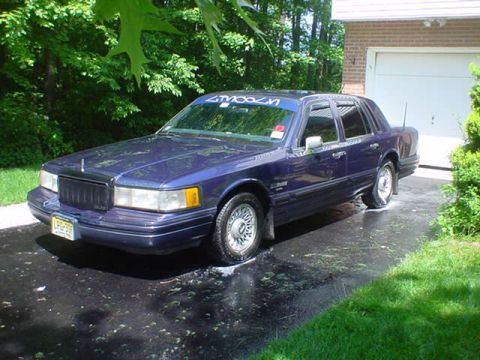 1994 Lincoln Town Car - A 1994 Lincoln Town Car is parked on a wet driveway next to a garage.