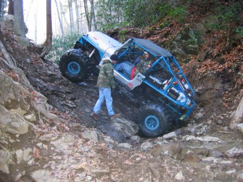 1992 Ford Mustang - A custom off-road buggy navigates a challenging, rocky incline in a wooded area.