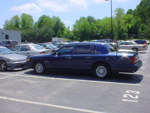 1994 Lincoln Town Car - This blue 1994 Lincoln Town Car is parked in a lot with other vehicles visible.