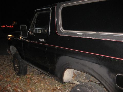 1991 Ford Bronco - Side view of a black Ford Bronco parked outdoors at night.