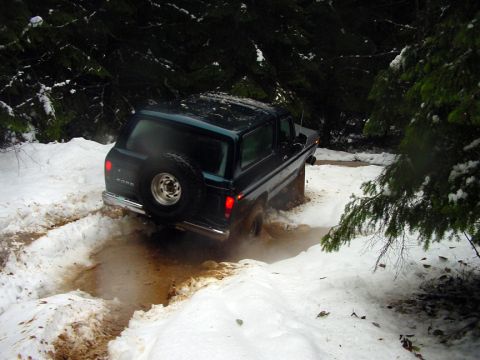 1979 Ford Bronco - A 1978 Ford Bronco navigates a challenging off-road path covered in snow and mud.