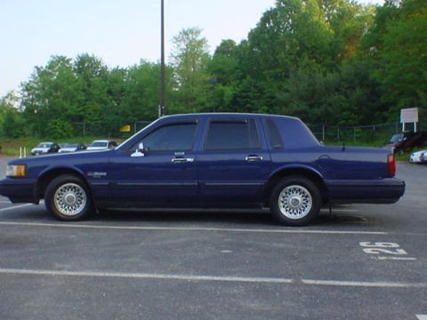 1994 Lincoln Town Car - Side profile of a blue 1994 Lincoln Town Car in a parking lot.
