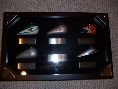 1987 Ford Bronco - A collection of motorcycle fuel tanks are displayed in a framed case, various designs and branding.