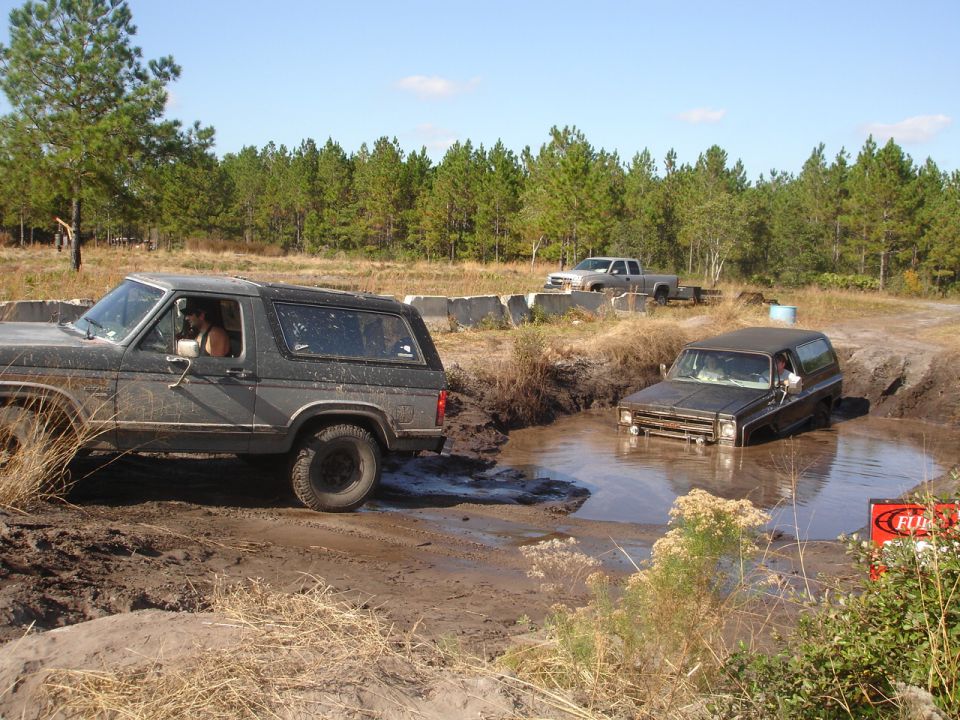 Ford Bronco driving out of mud pit next to Chevrolet K5 Blazer stuck in mud