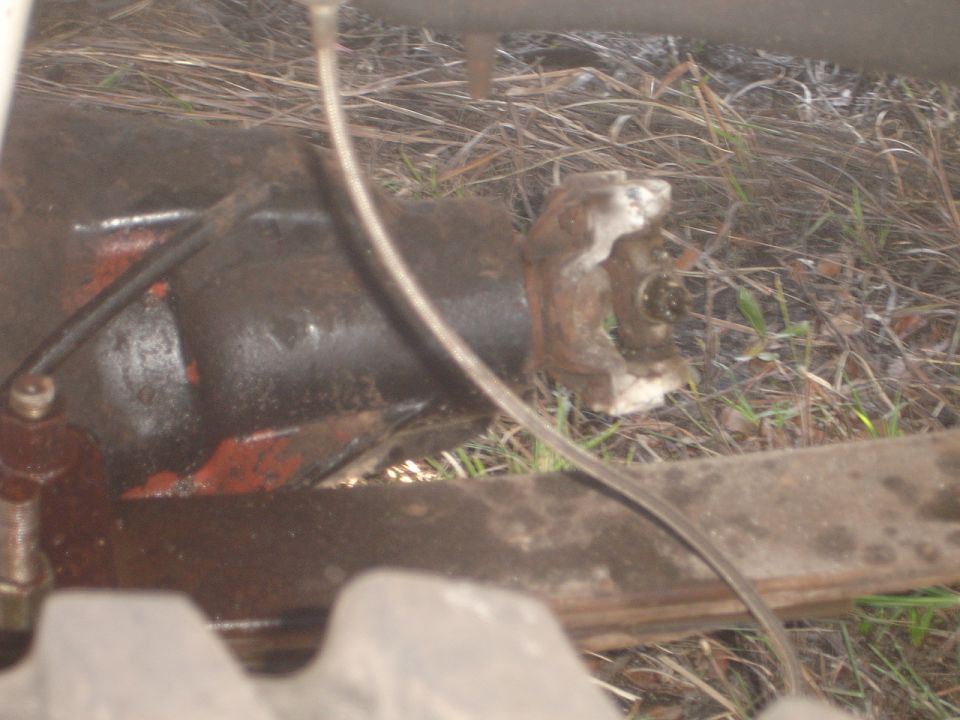 Close-up of a rusty driveshaft universal joint with a black housing and red paint