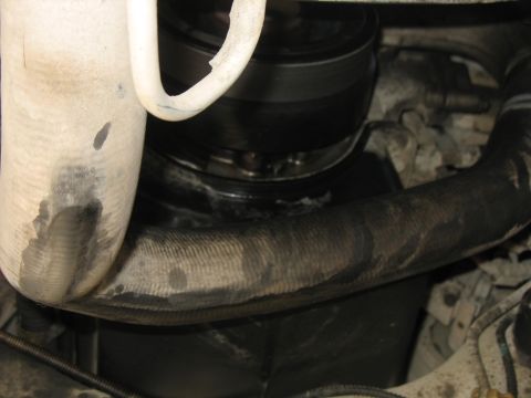 2001 Ford F-250 - This image shows a close-up view of engine components, including hoses and a pulley, with visible wear and tear.