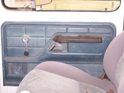 1979 Ford Bronco - Interior view of a 1979 Ford Bronco, showing the door panel with a manual window crank and armrest.