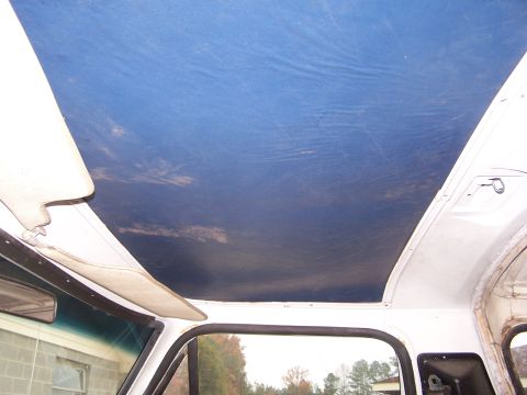 1979 Ford Bronco - The blue headliner of a vehicle's interior is visible, along with a sun visor.