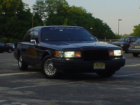 1994 Lincoln Town Car - A dark-colored Lincoln Town Car is parked in a lot with other vehicles visible in the background.