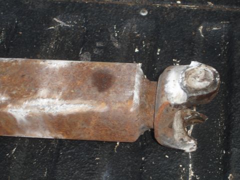 1989 Ford Bronco - A close-up view of a corroded metal component, likely a vehicle part, against a dark background.