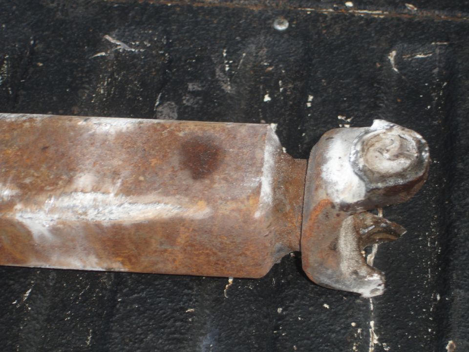 Rusted metal part with a silver connector, resting on a black textured surface