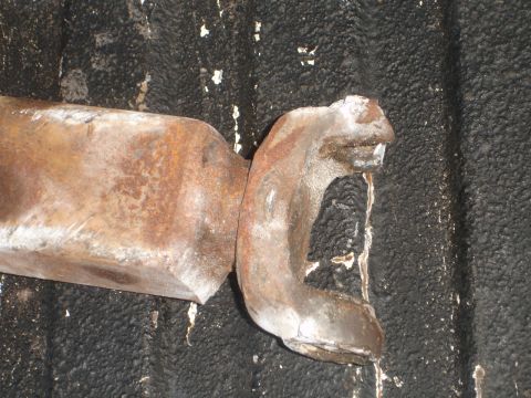 1989 Ford Bronco - A close-up view of a heavily rusted metal component, likely a vehicle part, against a dark, textured background.