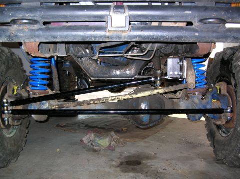 1985 Ford Bronco II - The front suspension and steering components of a vehicle are visible from underneath.
