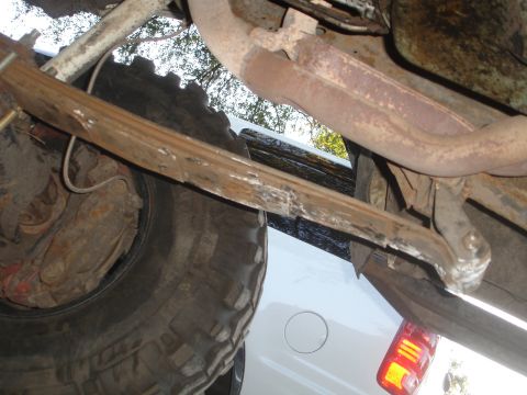 1989 Ford Bronco - An underside perspective reveals the suspension and exhaust system of a vehicle, with another white vehicle visible beneath.