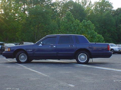 1994 Lincoln Town Car - Side profile of a blue 1994 Lincoln Town Car in a parking lot.