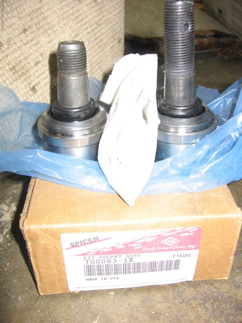 1989 Ford Bronco - Two new Spicer ball-joint socket assemblies with threaded studs sit unwrapped on blue tissue paper atop their cardboard box, which is label…