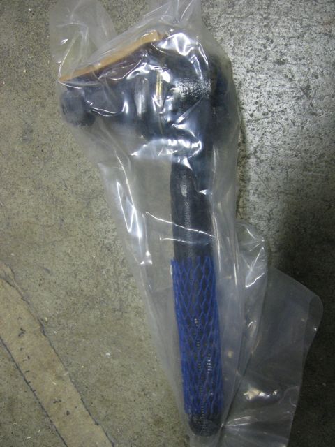 1989 Ford Bronco - A single automotive part is shown packaged in plastic, resting on a concrete floor.