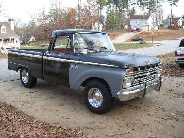 Black and gray 1966 Ford F-100 pickup parked in driveway, front-right view