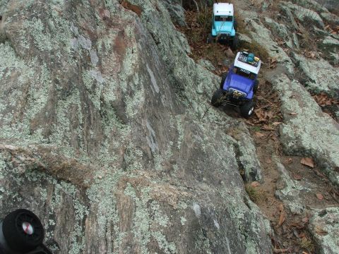 1996 Ford Bronco - Two toy trucks navigate a challenging rocky terrain on a hillside.