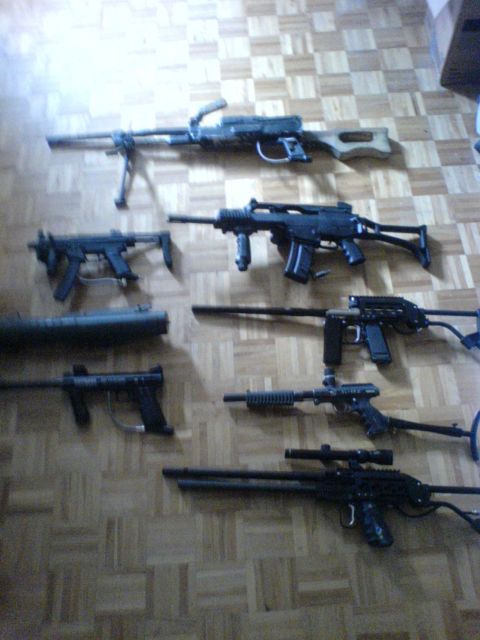 1985 Ford Bronco - A collection of firearms, including rifles and what appears to be a machine gun, are displayed on a wood-paneled floor.