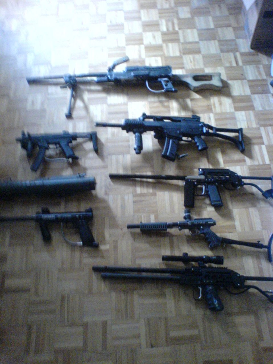 Various firearms laid out on a wooden floor