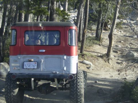 1986 Ford Bronco - Toyota Land Cruiser FJ40 with custom modifications driving on an off-road trail.