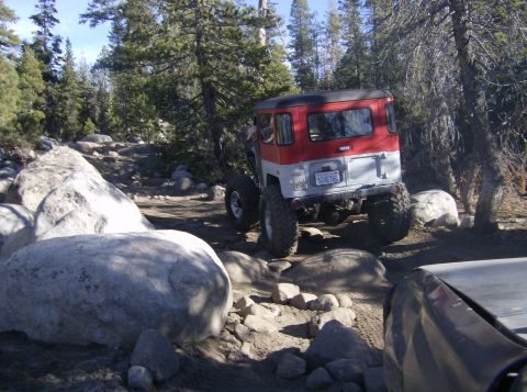 1986 Ford Bronco - This Toyota Land Cruiser is navigating a difficult, rocky off-road path through a forest.