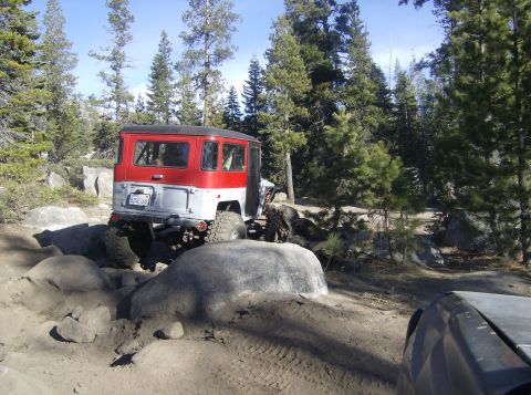 1986 Ford Bronco - Toyota Land Cruiser FJ40 navigating a difficult off-road trail with large rocks.