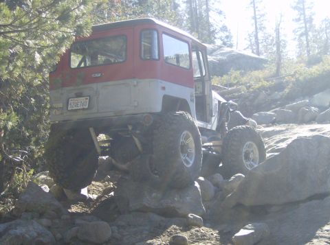 1986 Ford Bronco - This modified Toyota Land Cruiser FJ40 is navigating a rocky trail in a wooded area.