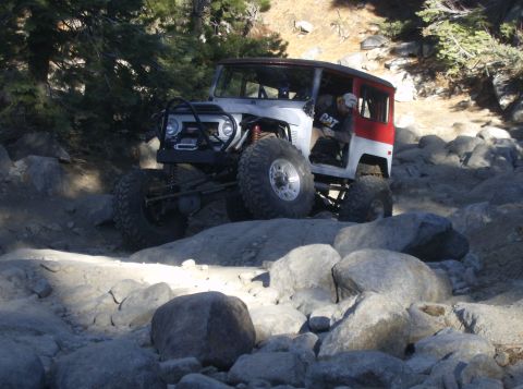1986 Ford Bronco - Off-road vehicle with custom modifications navigating a challenging rocky trail.