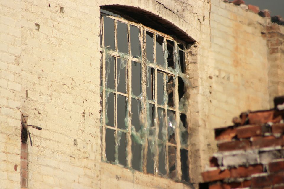 Broken multi-pane window in a weathered brick building wall