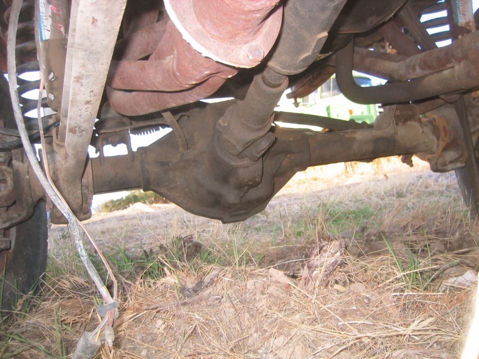 Underside view of solid front axle housing, tie rod and coil spring on a truck