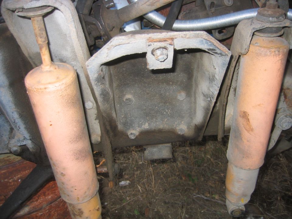 Two dusty yellow shock absorbers propped beside a rusty coil spring tower bracket