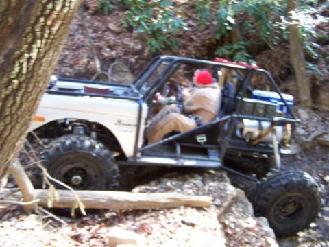 1992 Ford Mustang - Modified off-road buggy with a driver wearing a red hat navigates a challenging trail.
