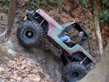 1992 Ford Mustang - An off-road vehicle with large tires navigates a challenging, wooded trail.