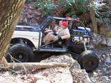 1992 Ford Mustang - This modified off-road vehicle is tackling a challenging, rocky path with two occupants.