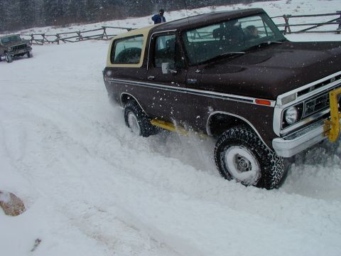 1979 Ford Bronco - A Ford Bronco navigates through deep snow, with another vehicle visible in the background.