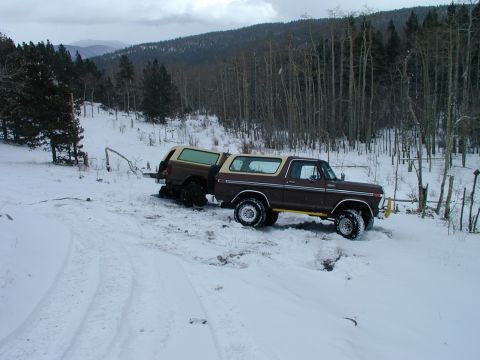 1979 Ford Bronco - A brown 1979 Ford Bronco tows a second Bronco through a snowy, wooded landscape.