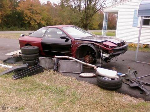1993 Ford Probe - A disassembled 1993 Ford Probe sits in a yard with parts scattered around it.