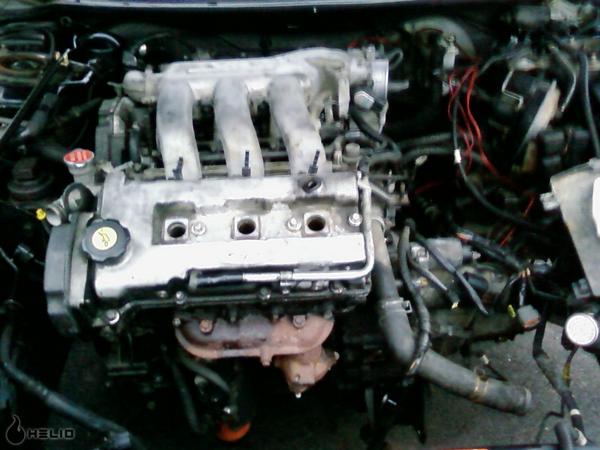 Engine bay with intake manifold and valve cover visible. Some wiring and hoses are present