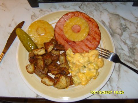 1989 Ford Bronco - A plate of food is shown with ham, pineapple, potatoes, and a pickle.