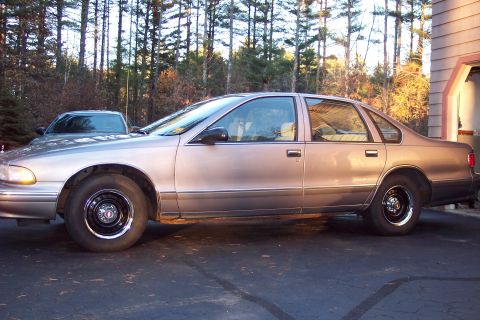 2001 Ford Crown Victoria - A tan 1995 Chevrolet Caprice sedan is parked in a driveway, with another vehicle visible behind it.