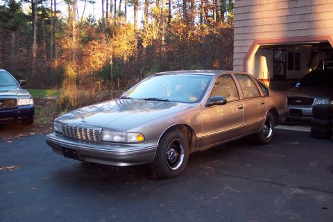 2001 Ford Crown Victoria - A tan 1995 Chevrolet Caprice sedan is parked in a driveway next to another vehicle.
