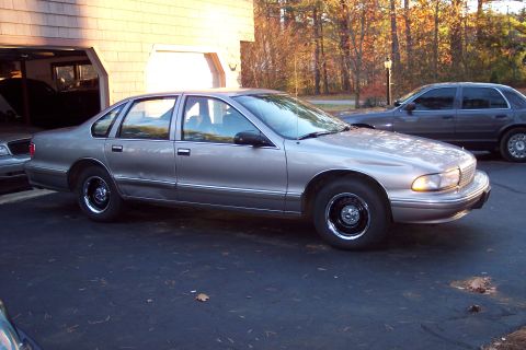 2001 Ford Crown Victoria - Side view of a 1990s Chevrolet Caprice sedan parked outside a garage.