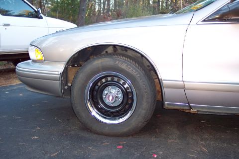 2001 Ford Crown Victoria - A silver sedan's front quarter panel and wheel are visible, parked next to a white SUV.
