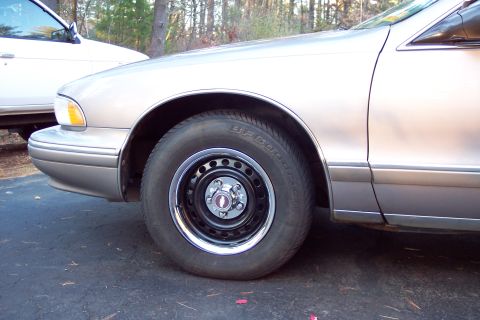 2001 Ford Crown Victoria - A silver sedan's front fender and wheel are visible, with another white vehicle in the background.