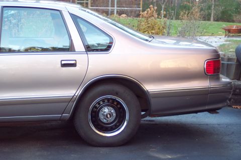 2001 Ford Crown Victoria - Rear side view of a tan sedan with a "GUARD" sticker on the window.