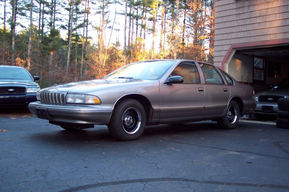 Brown Chevrolet Caprice parked outside a garage with another car visible inside
